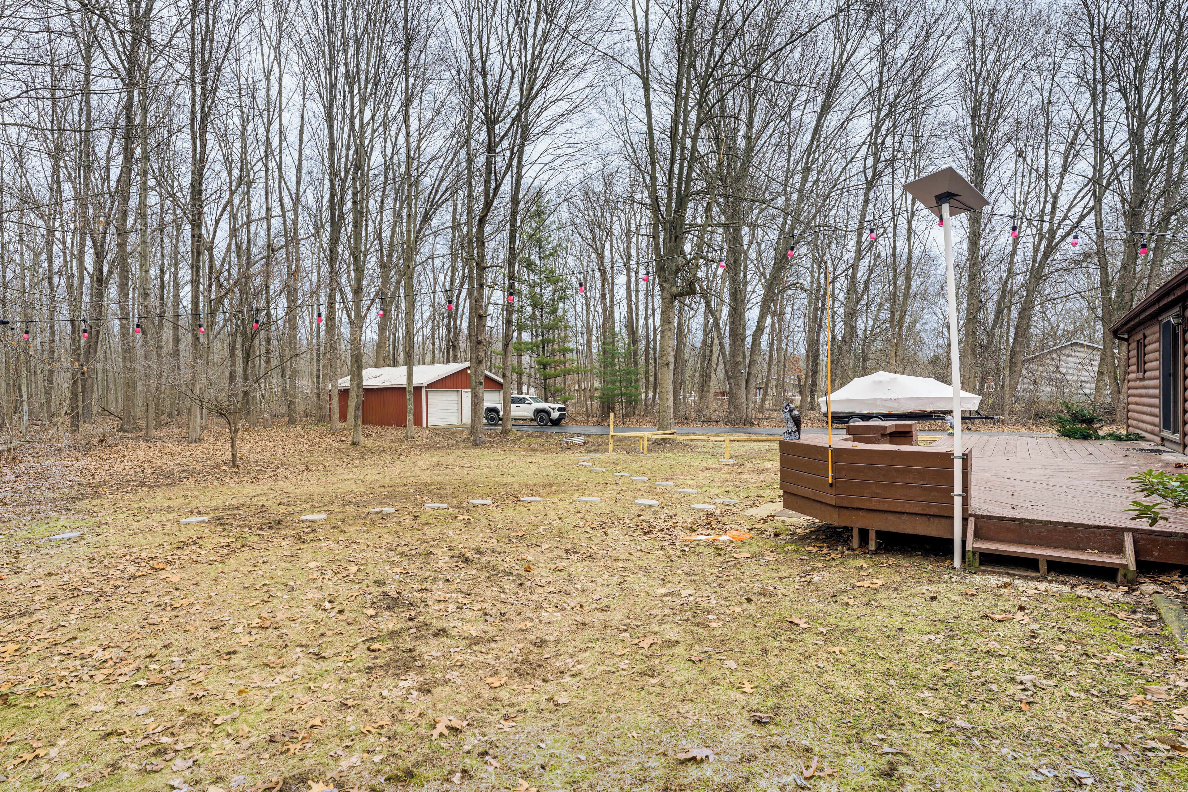Un espace boisé avec une terrasse en bois, un petit abri et une structure haute surmontée d’une lumière.
