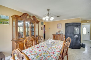 A dining area with a table set for four, surrounded by wooden chairs, a wooden cabinet with glass doors, and a black storage unit. - Fenced-in Yard + Patio: Pet-friendly Carriere Home (Carriere)