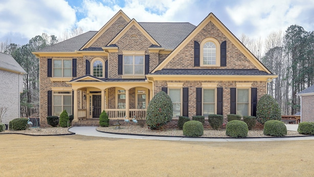 A two-story house with a brick facade, a gabled roof, and a front porch. - 7 Mi to Arthur Blank & Trilith Studios: Cozy Suite (Tyrone)