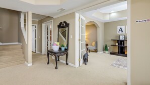 A hallway with a staircase, a console table with decorative items, a 'No Smoking' sign, and a Christmas tree. - 7 Mi to Arthur Blank & Trilith Studios: Cozy Suite (Tyrone)