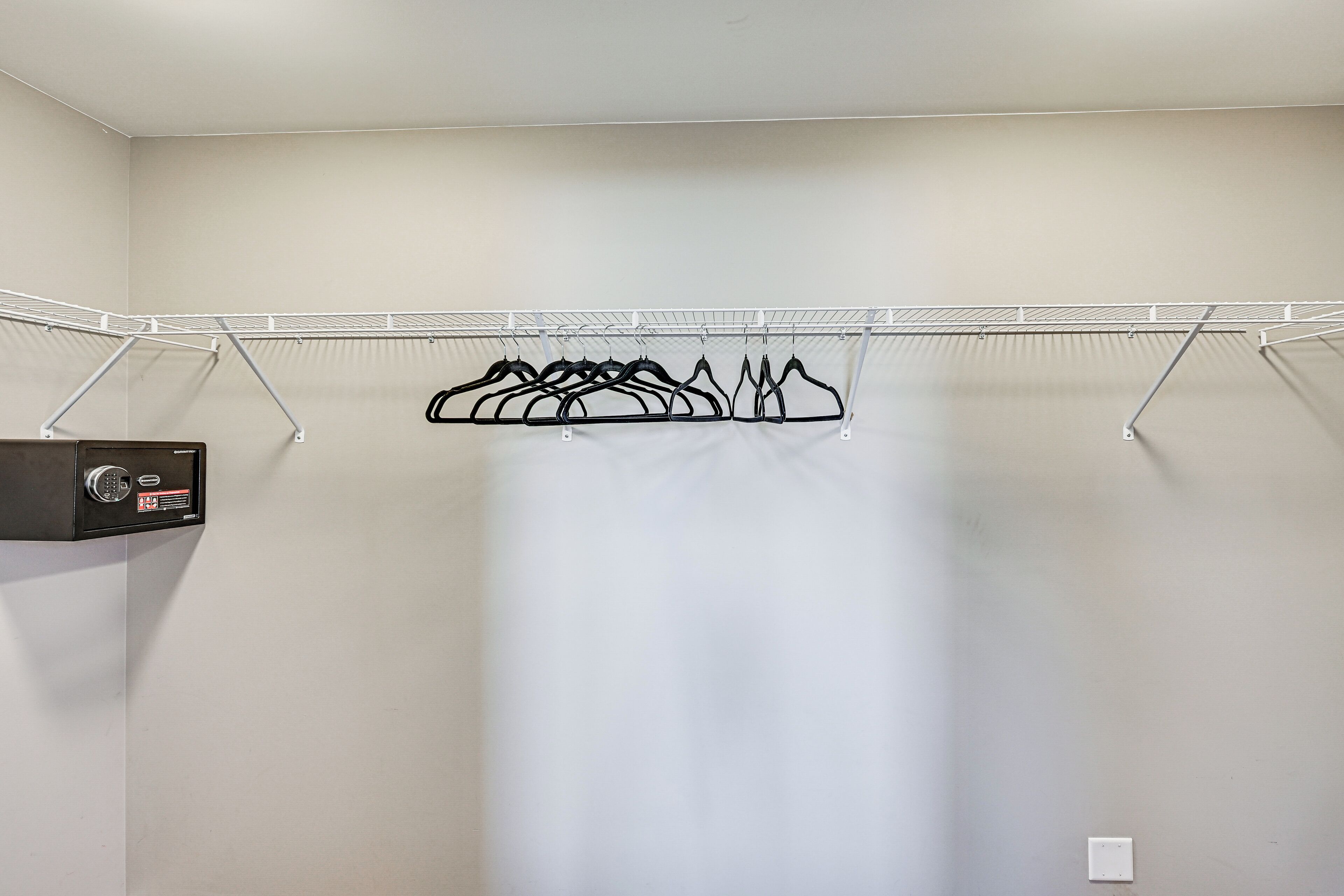 A closet with a metal drying rack and a black electronic device.