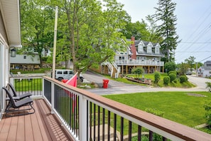 A residential property with a wooden deck, a front porch, and a large house with a chimney.