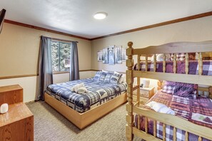 A bedroom with a wooden bed, a wooden nightstand, a window with curtains, and a wall with framed pictures. - Bear Canyon Getaway Hot Tub & Game Loft (Big Bear Lake)