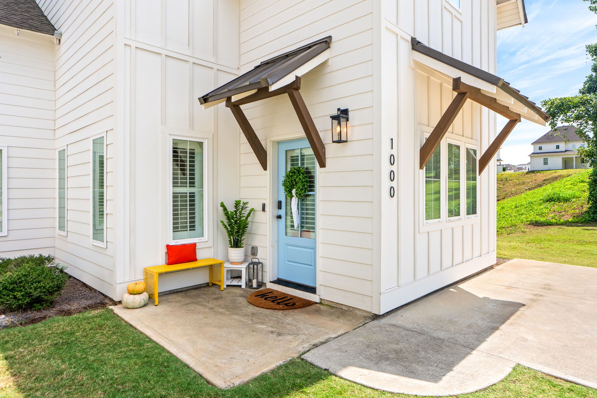 A two-story house with a blue front door, a bench, and a welcome mat.