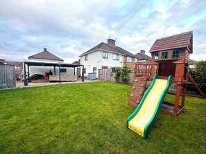 A backyard with a wooden play structure, a slide, and a covered seating area. - Entire House Ideal for UHW-Events-Stadium-City-Bay (Cardiff)