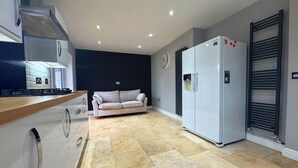 Una cocina moderna con horno integrado, refrigerador y comedor con sofá.