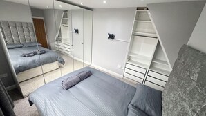 Un dormitorio con cama, armario y espejo.