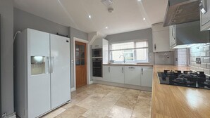 Una cocina moderna con armarios grises, horno empotrado, microondas y encimera de madera.