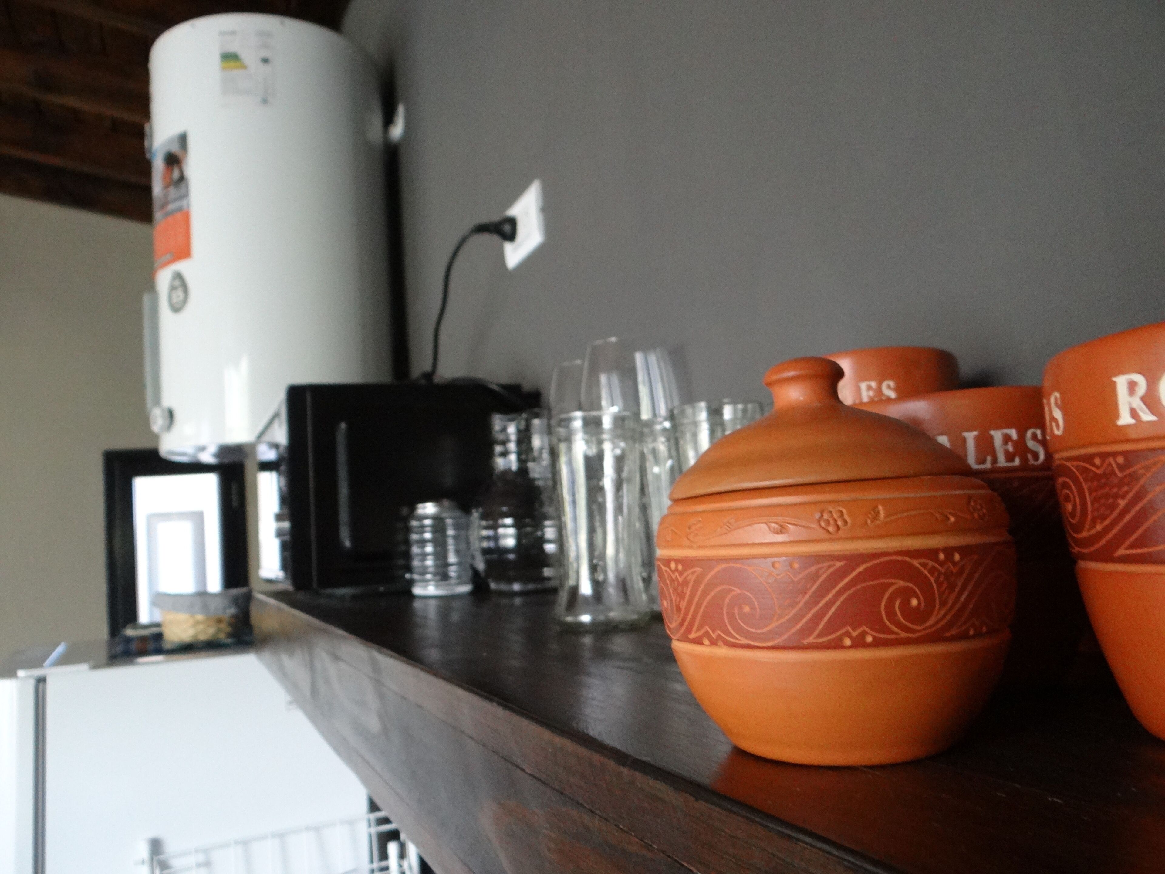 A kitchen counter with a coffee maker, glasses, and decorative pottery.