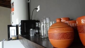 A kitchen counter with a coffee maker, glasses, and decorative pottery.