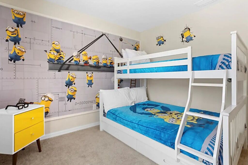 A bunk bed room with a Minion-themed wall and a yellow dresser.