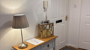 A small, white, wooden desk with a lamp, a paper, and a decorative box. - The Kinfirth - cosy beach apartment (Ayr)