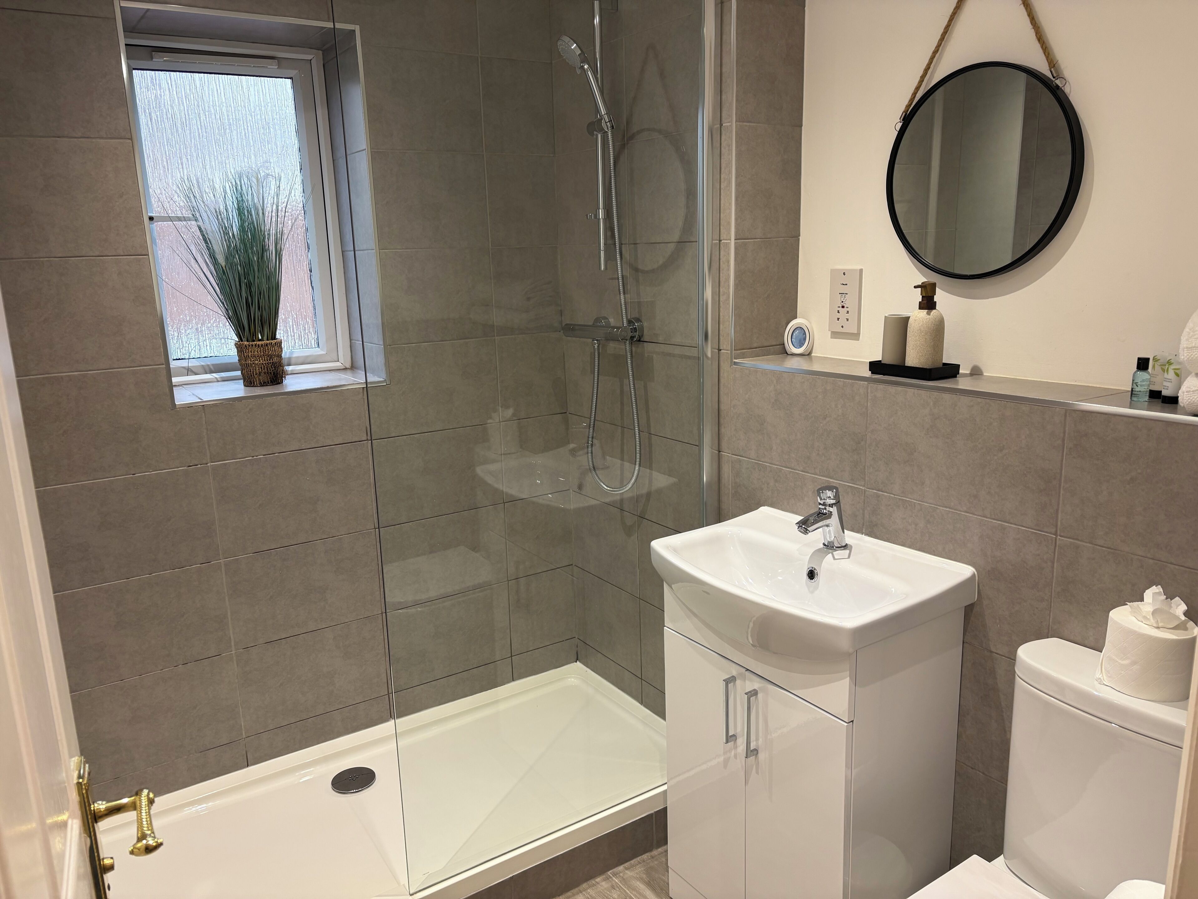 A modern bathroom with a glass-enclosed shower, a white sink, and a toilet.