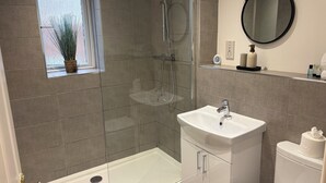 A modern bathroom with a glass-enclosed shower, a white sink, and a toilet. - The Kinfirth - cosy beach apartment (Ayr)