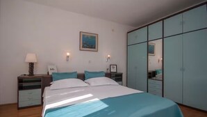Une chambre à coucher avec un lit, une table de chevet, une lampe, une armoire et un tableau accroché au mur.