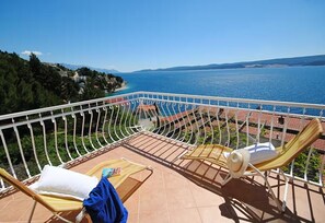 A balcony with two sun loungers, a tiled floor, and a view of the sea and distant hills. - Holiday Home Sunny (Čelina)