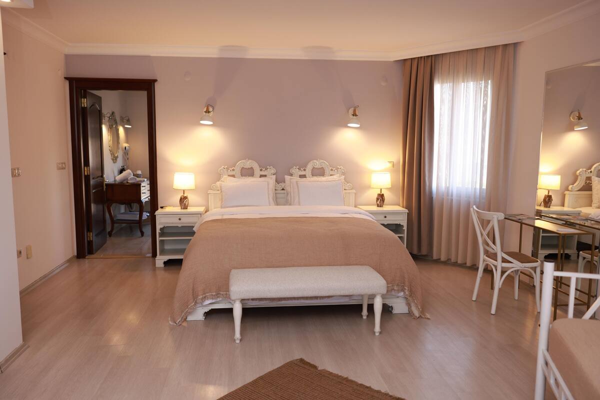 A bedroom with a large bed, bedside tables, a desk, and a chair.