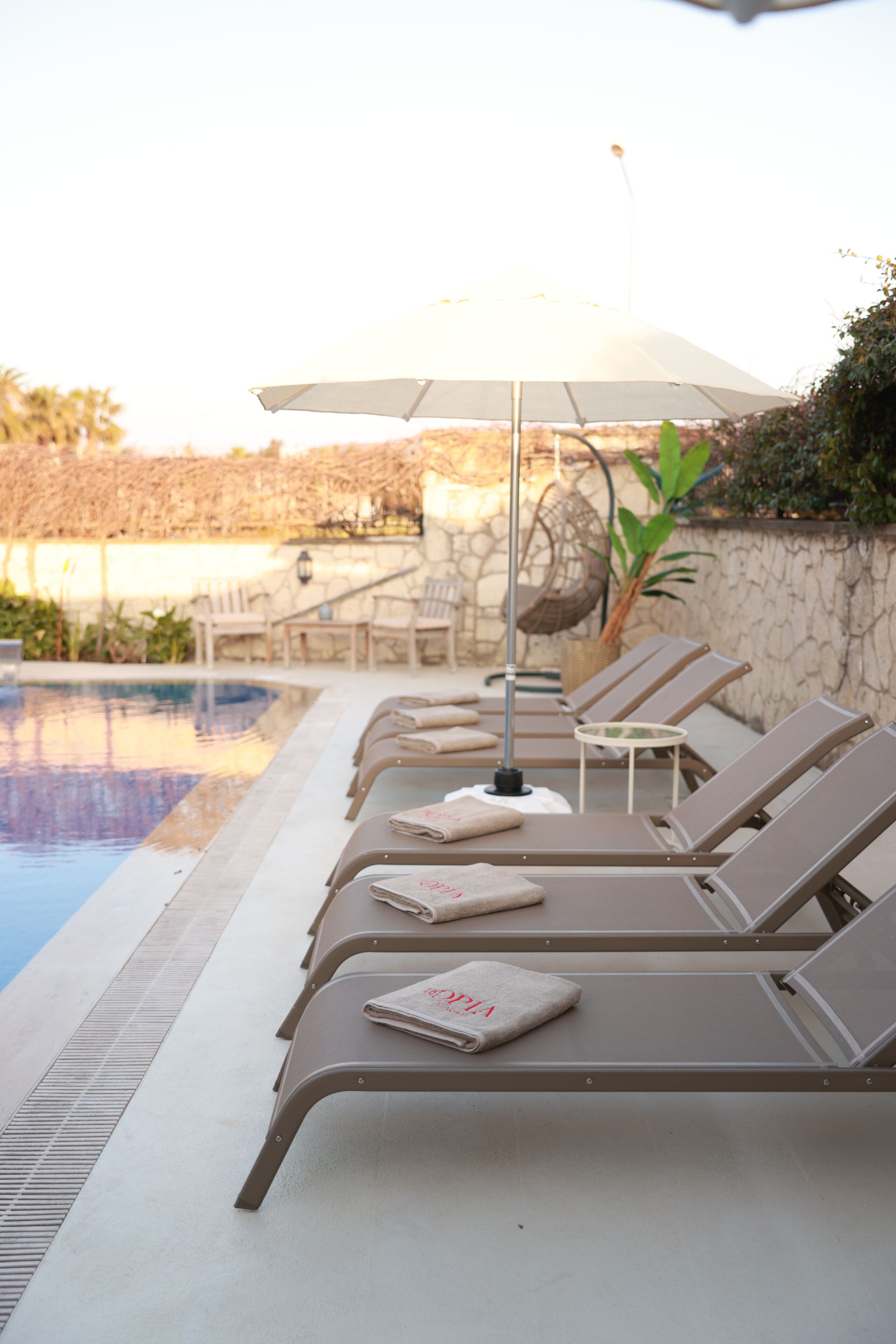 Un espace aménagé au bord de la piscine, avec des chaises longues, une table et un parasol.