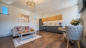 Een moderne woonkamer met een bank, salontafel en een eethoek met een stoel.