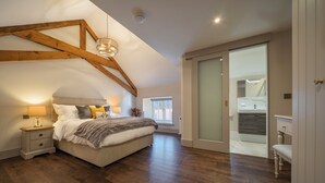 Een slaapkamer met een bed, nachtkastjes, een kledingkast en een glazen schuifdeur naar een badkamer.