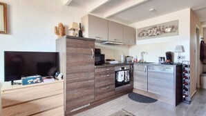 A modern kitchen with a TV, cabinets, and a wine rack. - Saint Vincent near beach all comforts (le Grau D'Agde)