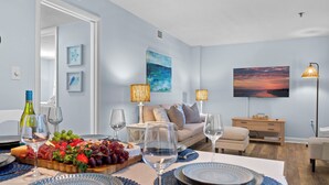 A modern living room with a dining area, featuring a sofa, coffee table, and a flat-screen TV. - Family Friendly Resort w/ Pools, Beach, Golf (Hilton Head Island)