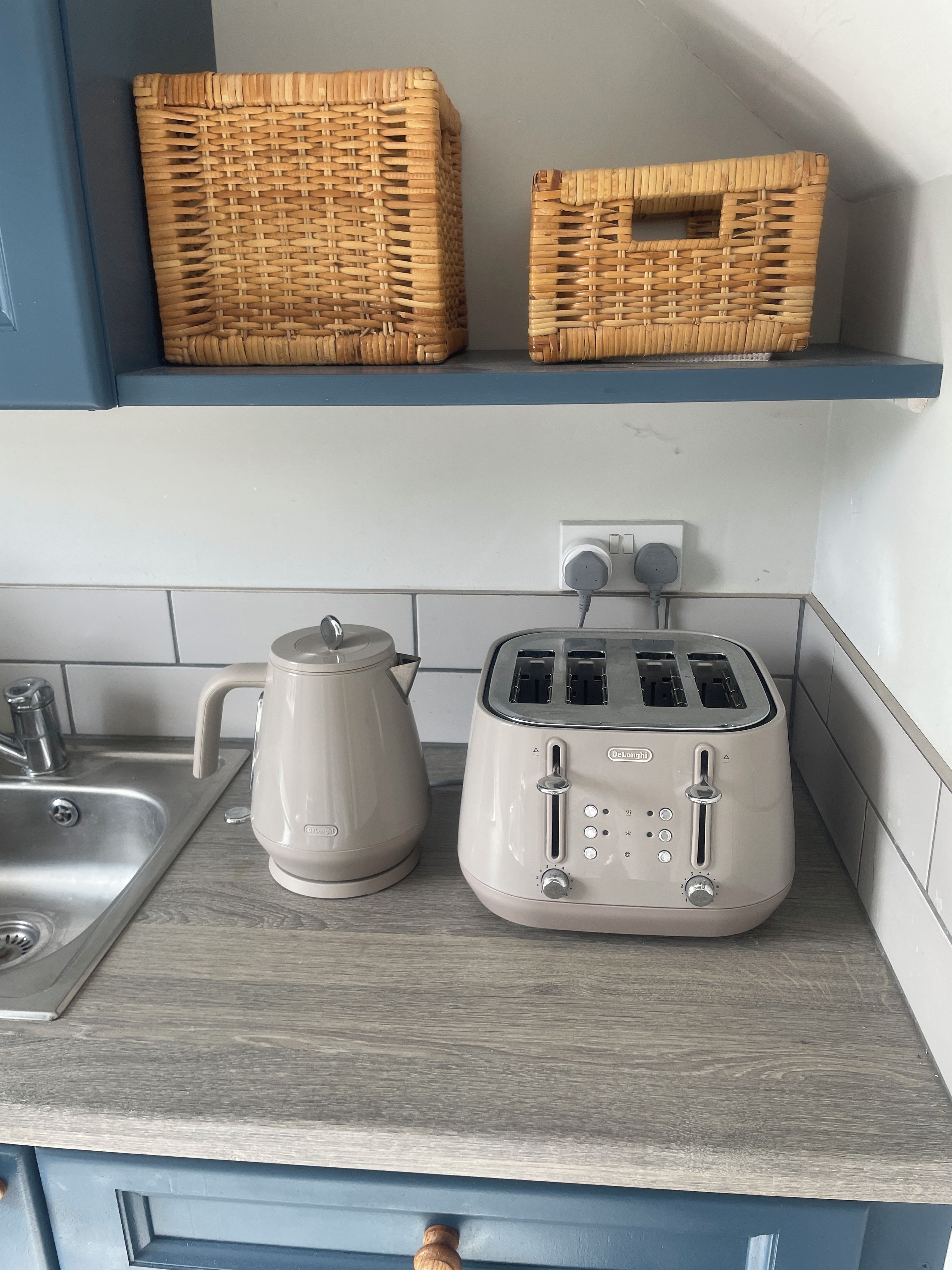 A kitchen counter with a kettle, toaster, and two wicker baskets.