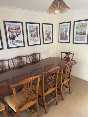 Una sala de conferències amb una taula de fusta llarga i sis cadires, cartells enmarcats a la paret i una lluminària al sostre.