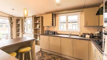 Une cuisine moderne avec un parquet disposé en chevrons, un four à micro-ondes encastré et une fenêtre donnant sur l’extérieur.
