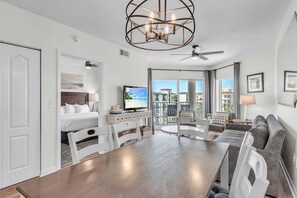 A hotel room with a dining area, a bed, a television, and a balcony with a view. - 🌴Beachfront Pool/Hot Tub🐬Direct Beach Access🐠Sunset Vistas 605N (Treasure Island)