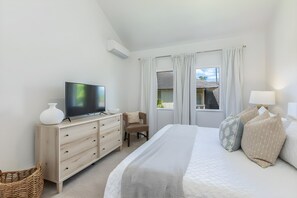 A hotel room with a bed, a TV, a desk, and a window with curtains. - Poipu, Regency at Poipu Kai, Spacious 6 BR, Ocean View, Sleeps 16 (Koloa)