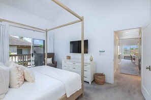 A bedroom with a four-poster bed, a flat-screen TV, a dresser, and a view of the outside. - Poipu, Regency at Poipu Kai, Spacious 6 BR, Ocean View, Sleeps 16 (Koloa)