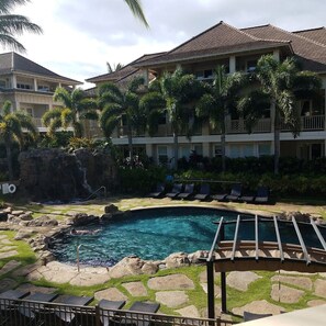 A hotel with a swimming pool surrounded by palm trees and lounge chairs. - Poipu Kai - 6BR Villas, Pool - Sleeps 16 (Koloa)