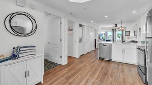Una cocina moderna con armarios blancos, una isla central y un espejo grande.