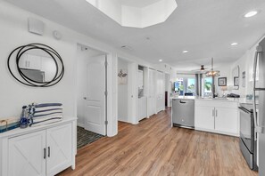 A modern kitchen with white cabinetry, a central island, and a large mirror. - 🌴Large Pool-2 Hot Tubs🐬Beach Access Onsite☀Sunset Vistas 302N (Treasure Island)