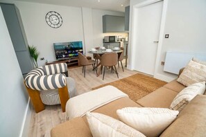 A modern living room with a sofa, striped armchair, and a dining area with chairs and a table.