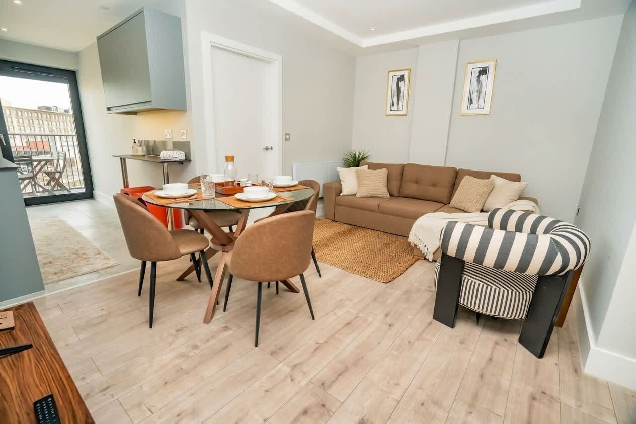 Un salon moderne comprenant un coin repas, un canapé et un fauteuil à rayures.