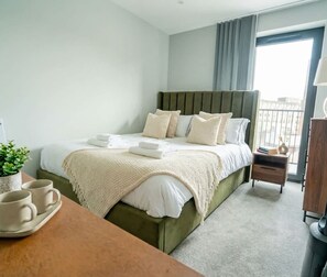 A hotel room with a bed, bedside table, and a view of the outside.