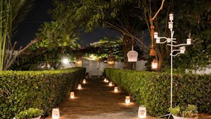 A stone pathway flanked by neatly trimmed hedges and potted plants, leading to a building entrance. - Kabara Garden Oasis in Aegina BBQ Priv Parking (Aegina)