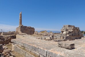 Ancient ruins with stone structures and a tall pillar. - Kabara Garden Oasis in Aegina BBQ Priv Parking (Aegina)