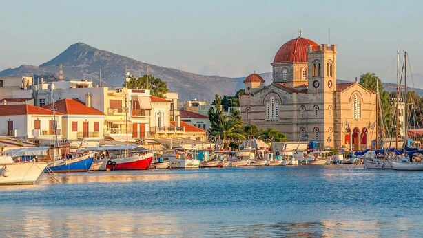 A coastal town with a prominent church, boats docked in the harbor, and a mountain in the background. - Kabara Garden Oasis in Aegina BBQ Priv Parking (Aegina)