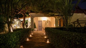 A stone pathway leading to a building with a door, surrounded by greenery and lit by lanterns. - Kabara Garden Oasis in Aegina BBQ Priv Parking (Aegina)