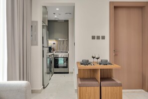 Eine moderne Küche mit Edelstahlgeräten, einem Holzesstisch mit einer Bank und einer Holztür.