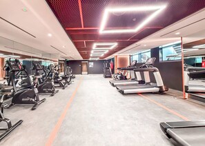Ein Fitnessstudio mit Laufbändern, Crosstrainern und Gewichten.