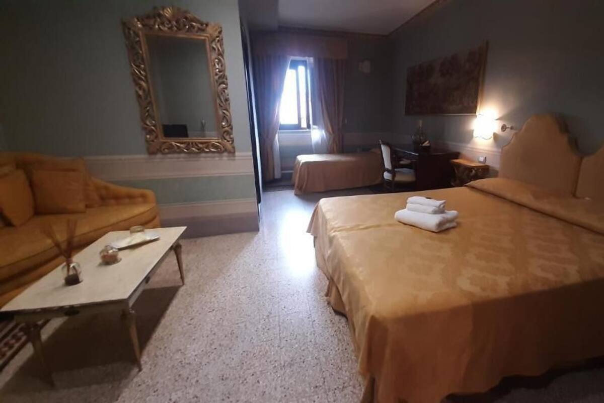 Ein Hotelzimmer mit Bett, einer Couch, einem Schreibtisch, einem Stuhl und einem großen Spiegel.