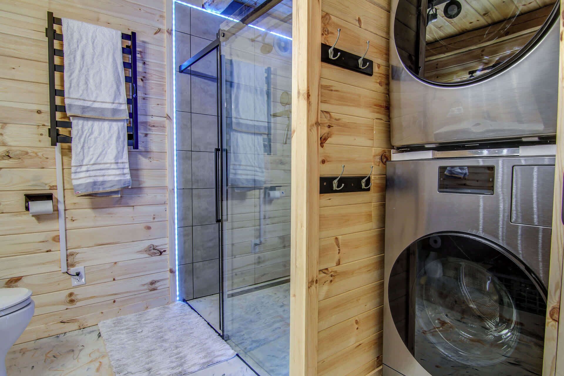 Un intérieur en bois avec une douche en verre, des toilettes et un lave-linge.