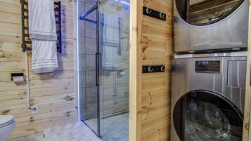 Un intérieur en bois avec une douche en verre, des toilettes et un lave-linge.