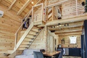 A wooden cabin interior with a staircase, a dining area, and a kitchen. - Nature & SPA | Chalet du Sommet (Sainte-Rose-du-Nord)