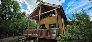 A wooden cabin with a balcony, surrounded by trees.