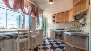 A kitchen with a checkered floor, wooden cabinets, a gas stove, and a window with curtains. - Cozy Penthouse with Terrace (Rome)